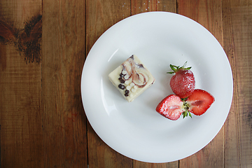 Image showing cut strawberries on the white plate and cake