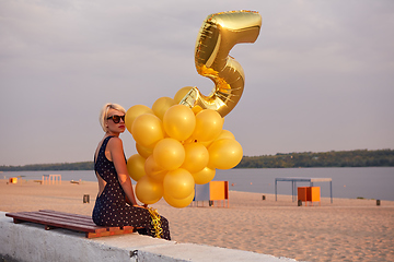 Image showing Young woman with many golden balloons.