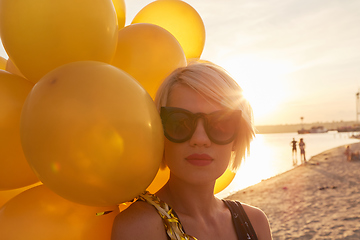 Image showing Young woman with many golden balloons.