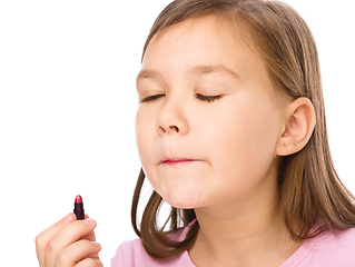 Image showing Little girl is applying lipstick