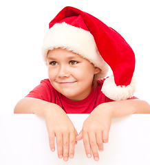 Image showing Little girl in santa hat is holding blank board