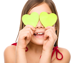 Image showing Little girl is holding hearts over her eyes