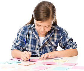 Image showing Girl is writing on color stickers using pen