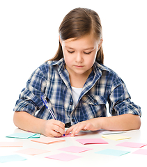 Image showing Girl is writing on color stickers using pen