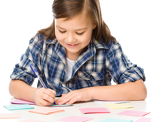 Image showing Girl is writing on color stickers using pen