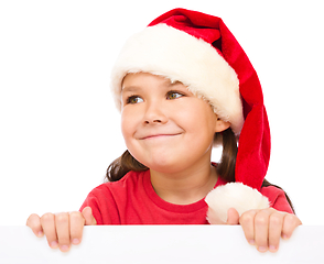 Image showing Little girl in santa hat is holding blank board