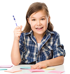 Image showing Girl is writing on color stickers using pen