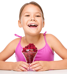 Image showing Happy little girl is eating raspberries