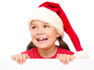 Image showing Little girl in santa hat is holding blank board