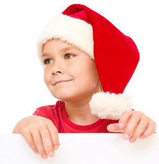 Image showing Little girl in santa hat is holding blank board