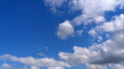 Image showing Time lapse Fluffy clouds float across the blue sky.
