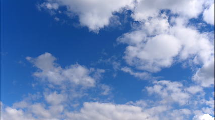 Image showing Time lapse Fluffy clouds float across the blue sky.