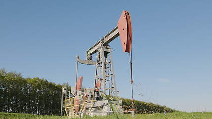 Image showing Operating oil and gas well in oil field, profiled against the blue sky