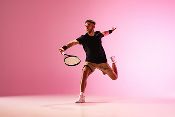 Image showing Young caucasian man playing tennis isolated on pink studio background, action and motion concept