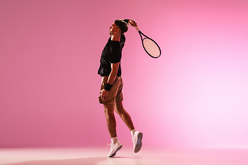 Image showing Young caucasian man playing tennis isolated on pink studio background, action and motion concept