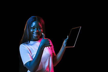 Image showing African young woman\'s portrait on dark studio background in neon. Concept of human emotions, facial expression, youth, sales, ad.