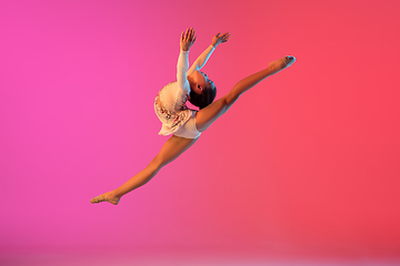 Image showing African-american rhythmic gymnast, pretty girl practicing on gradient studio background in neon light