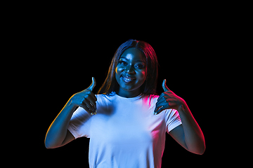 Image showing African young woman\'s portrait on dark studio background in neon. Concept of human emotions, facial expression, youth, sales, ad.