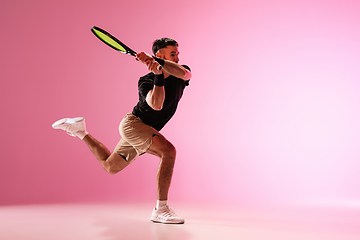 Image showing Young caucasian man playing tennis isolated on pink studio background, action and motion concept