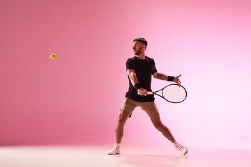 Image showing Young caucasian man playing tennis isolated on pink studio background, action and motion concept