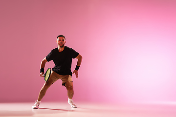 Image showing Young caucasian man playing tennis isolated on pink studio background, action and motion concept