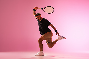 Image showing Young caucasian man playing tennis isolated on pink studio background, action and motion concept