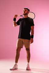 Image showing Young caucasian man playing tennis isolated on pink studio background, action and motion concept