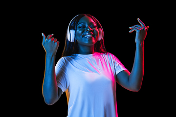 Image showing African young woman\'s portrait on dark studio background in neon. Concept of human emotions, facial expression, youth, sales, ad.