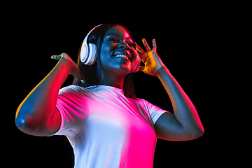 Image showing African young woman\'s portrait on dark studio background in neon. Concept of human emotions, facial expression, youth, sales, ad.