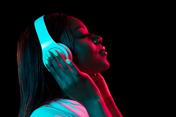 Image showing African young woman\'s portrait on dark studio background in neon. Concept of human emotions, facial expression, youth, sales, ad.