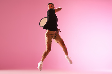 Image showing Young caucasian man playing tennis isolated on pink studio background, action and motion concept