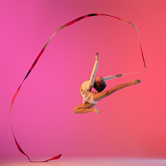 Image showing African-american rhythmic gymnast, pretty girl practicing on gradient studio background in neon light