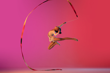 Image showing African-american rhythmic gymnast, pretty girl practicing on gradient studio background in neon light