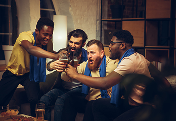 Image showing Group of friends watching TV, sport match together. Emotional fans cheering for favourite team, watching on exciting game.