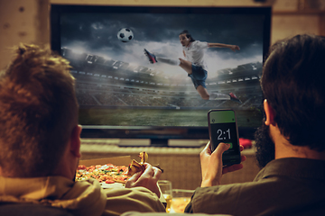 Image showing Men with betting application in phone. Group of friends watching TV, sport match together. Emotional fans cheering for favourite team, watching on exciting game.