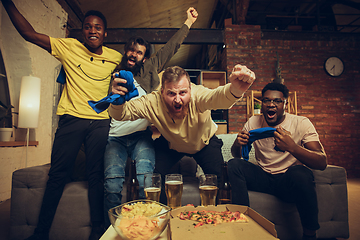 Image showing Group of friends watching TV, sport match together. Emotional fans cheering for favourite team, watching on exciting game.