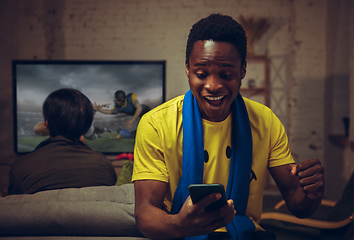 Image showing Man with betting application in phone. Group of friends watching TV, sport match together. Emotional fans cheering for favourite team, watching on exciting game.