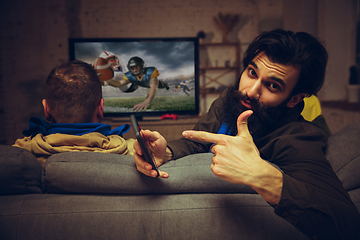 Image showing Man with betting application in phone. Group of friends watching TV, sport match together. Emotional fans cheering for favourite team, watching on exciting game.