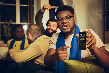 Image showing Group of friends watching TV, sport match together. Emotional fans cheering for favourite team, watching on exciting game.