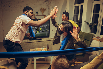 Image showing Group of friends watching TV, sport match together. Emotional fans cheering for favourite team, watching on exciting game.