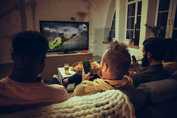 Image showing Group of friends watching TV, sport match together. Emotional fans cheering for favourite team, watching on exciting game.