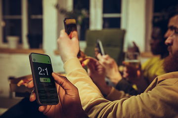 Image showing Group of friends watching TV, sport match together. Emotional fans cheering for favourite team, watching on exciting game.