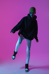 Image showing Young stylish man in modern street style outfit isolated on gradient background in neon light. African-american fashionable model in look book, musician performing.