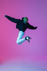 Image showing Young stylish man in modern street style outfit isolated on gradient background in neon light. African-american fashionable model in look book, musician performing.