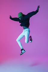 Image showing Young stylish man in modern street style outfit isolated on gradient background in neon light. African-american fashionable model in look book, musician performing.