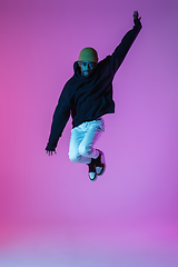 Image showing Young stylish man in modern street style outfit isolated on gradient background in neon light. African-american fashionable model in look book, musician performing.