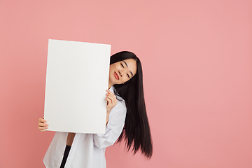 Image showing Asian young woman\'s portrait on pink studio background. Concept of human emotions, facial expression, youth, sales, ad.