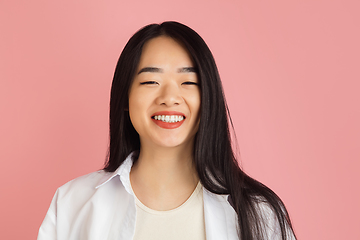 Image showing Asian young woman\'s portrait on pink studio background. Concept of human emotions, facial expression, youth, sales, ad.