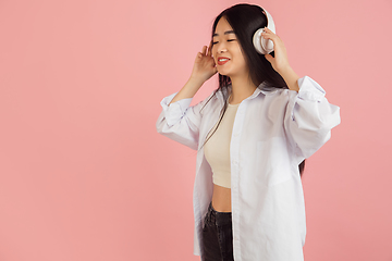 Image showing Asian young woman\'s portrait on pink studio background. Concept of human emotions, facial expression, youth, sales, ad.