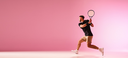 Image showing Young caucasian man playing tennis isolated on pink studio background, action and motion concept